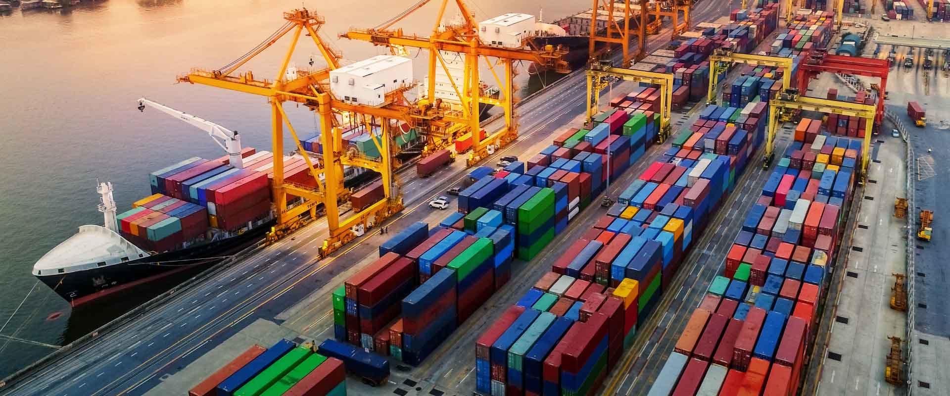 Containerschip en kranen in een haven bij zonsondergang
